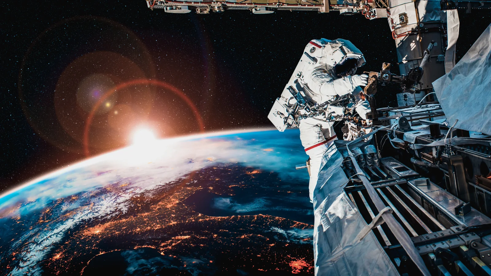 Astronaut working outside the International Space Station above Earth at sunrise