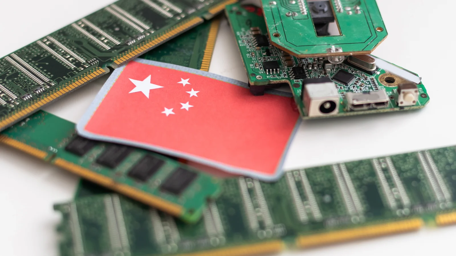 A Chinese flag resting on computer memory modules and a circuit board, illustrating China's CXMT moving into NAND flash alongside DRAM.
