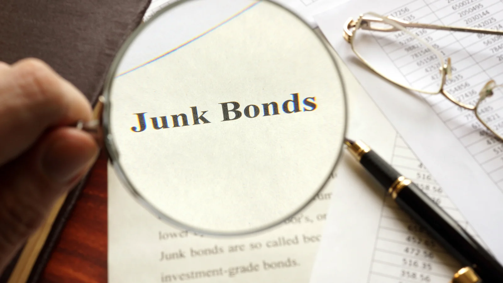 A magnifying glass over the words Junk Bonds on a printed page