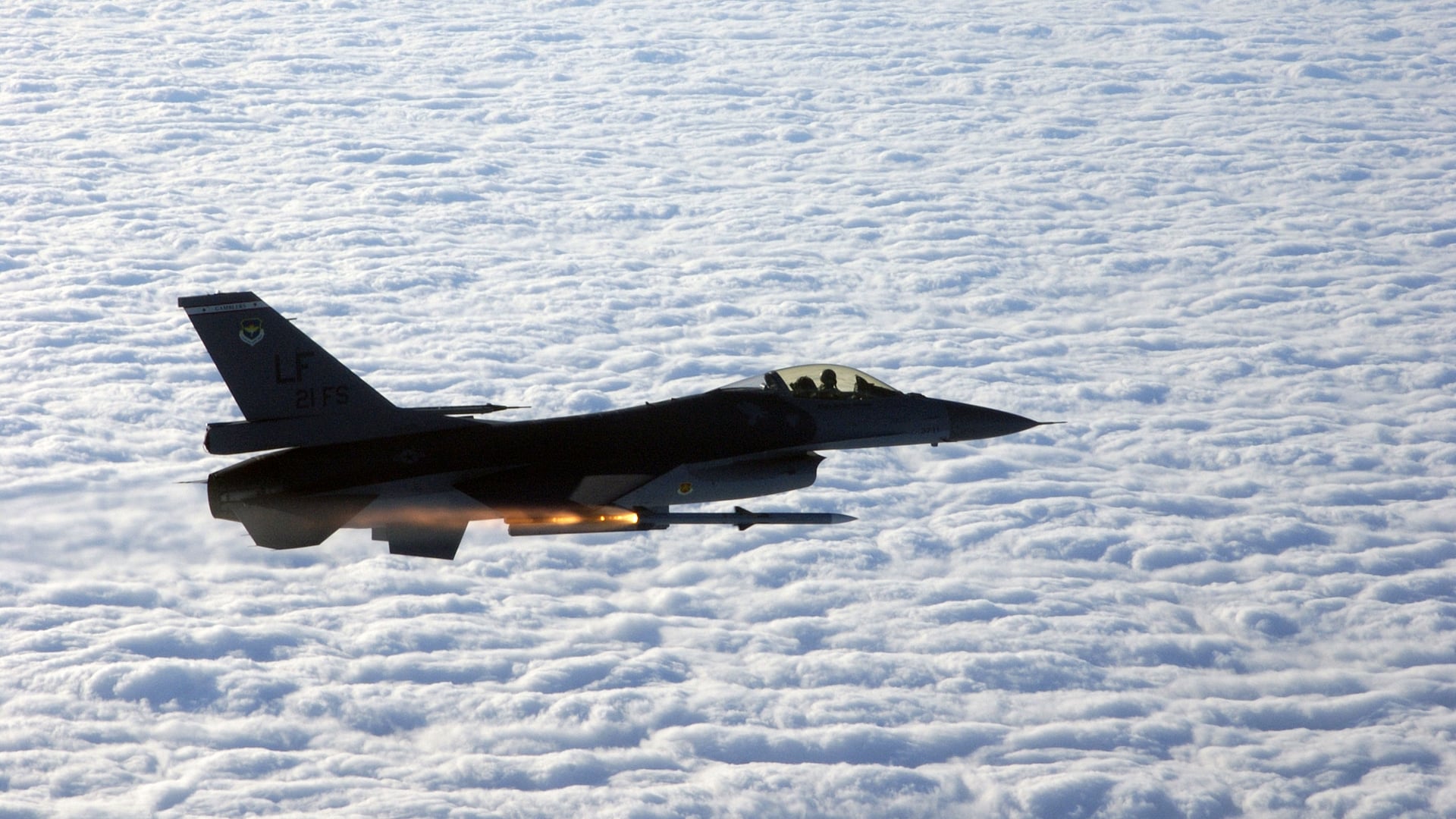 A U.S. Air Force F-16C from the 21st Fighter Squadron launches an AIM-120 AMRAAM missile above the clouds